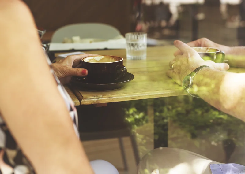 Mesera sirviendo café sostenible a una pareja en un ambiente natural